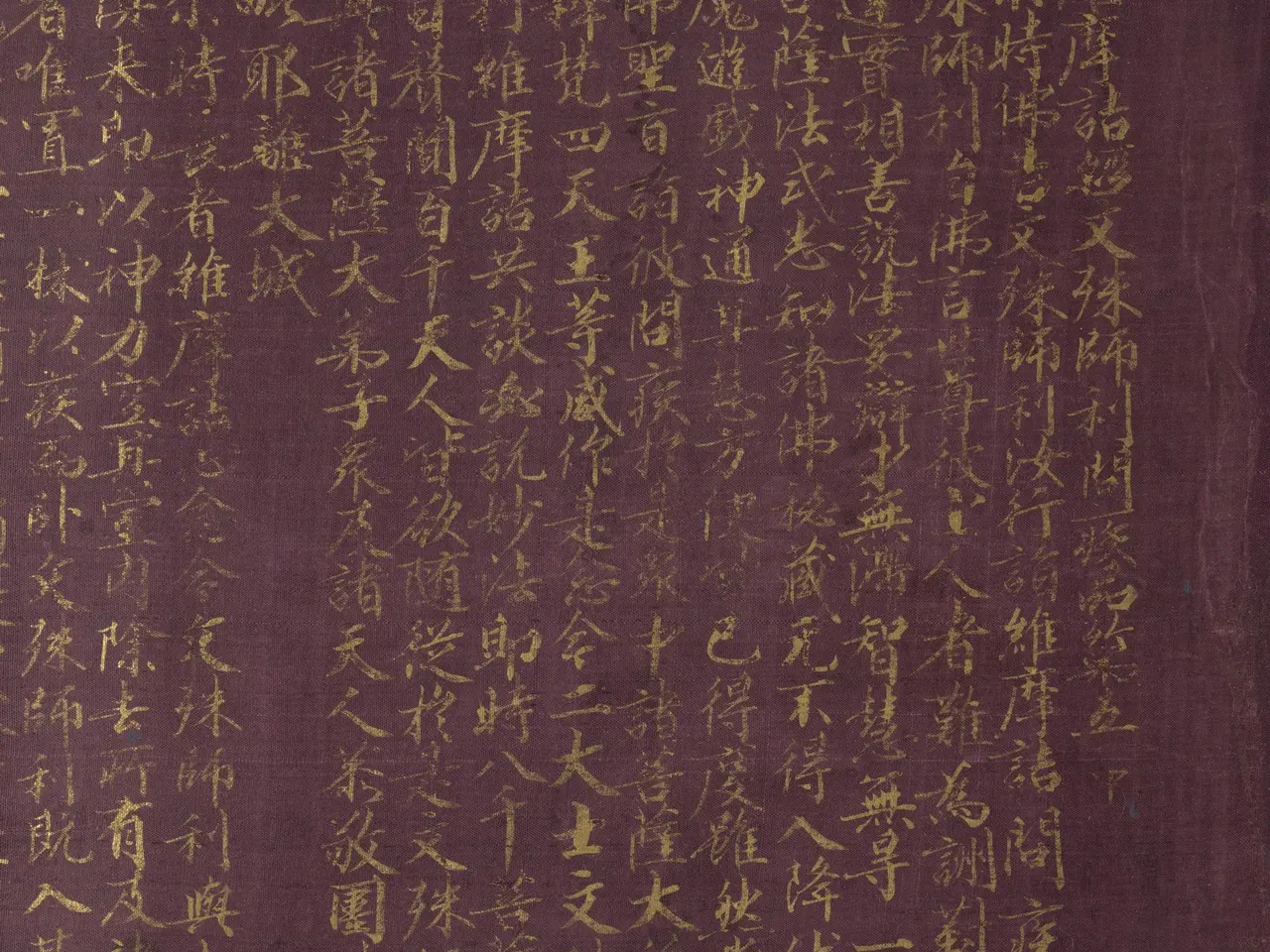 紫紙金字的維摩詰經手卷局部，左側是整齊的小楷經文，右側是說法圖
